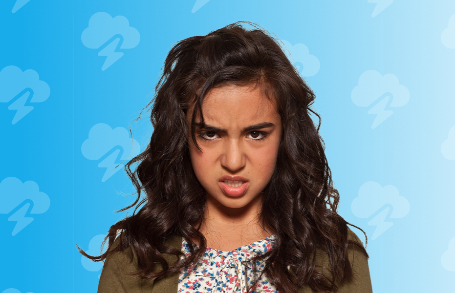 A teenager against a blue background looking directly ahead with an angry expression.